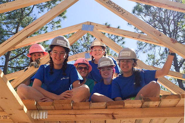 A group of GT young women students sitting on the roof of a house under construction.