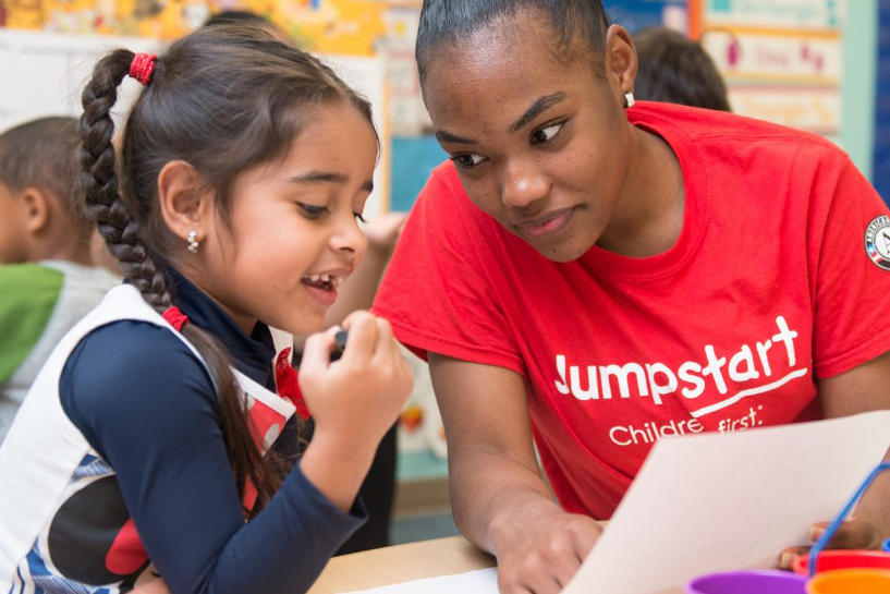 A Jumpstart volunteer helps a child with homework.